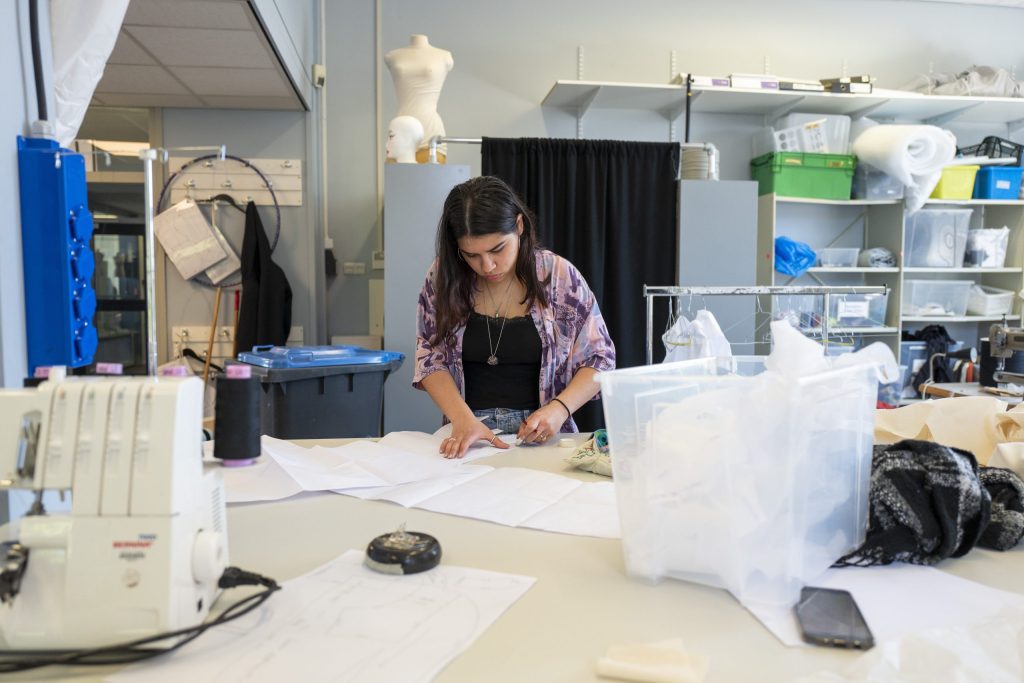 Student in het mbo werkt aan een mode- of ontwerpproject in een praktijklokaal.