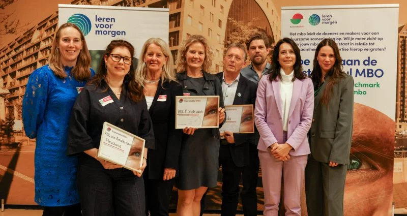 Groepsfoto van vertegenwoordigers van verschillende onderwijsinstellingen die een certificaat ontvangen tijdens een bijeenkomst van Leren voor Morgen over duurzaam mbo-onderwijs.