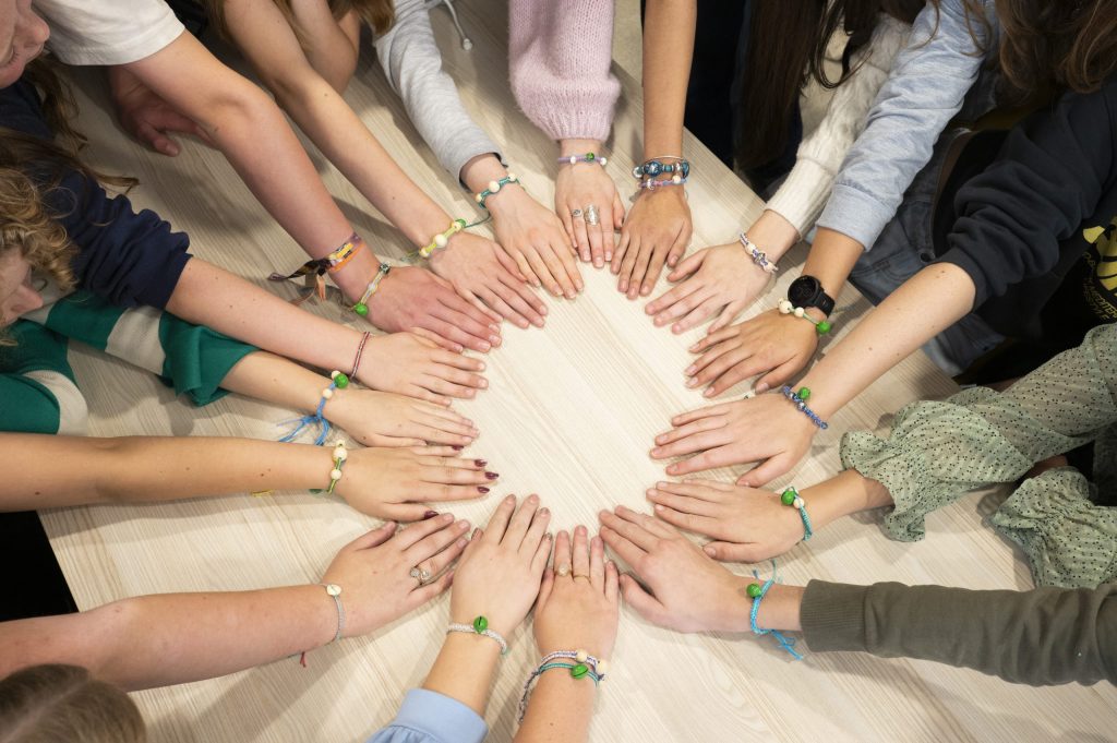 Groep mensen legt hun handen samen op tafel als symbool voor samenwerking binnen de coöperatie Leren voor Morgen.
