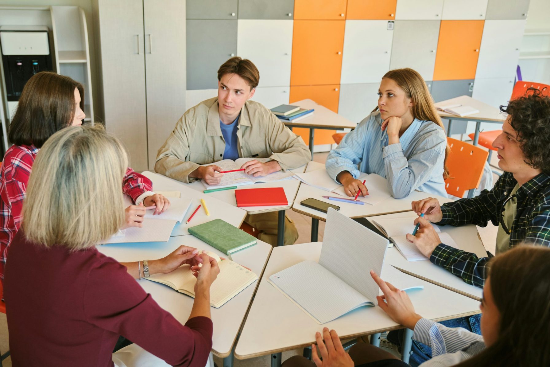 Studenten en docent in het hoger onderwijs overleggen in kleine groep tijdens een werksessie.